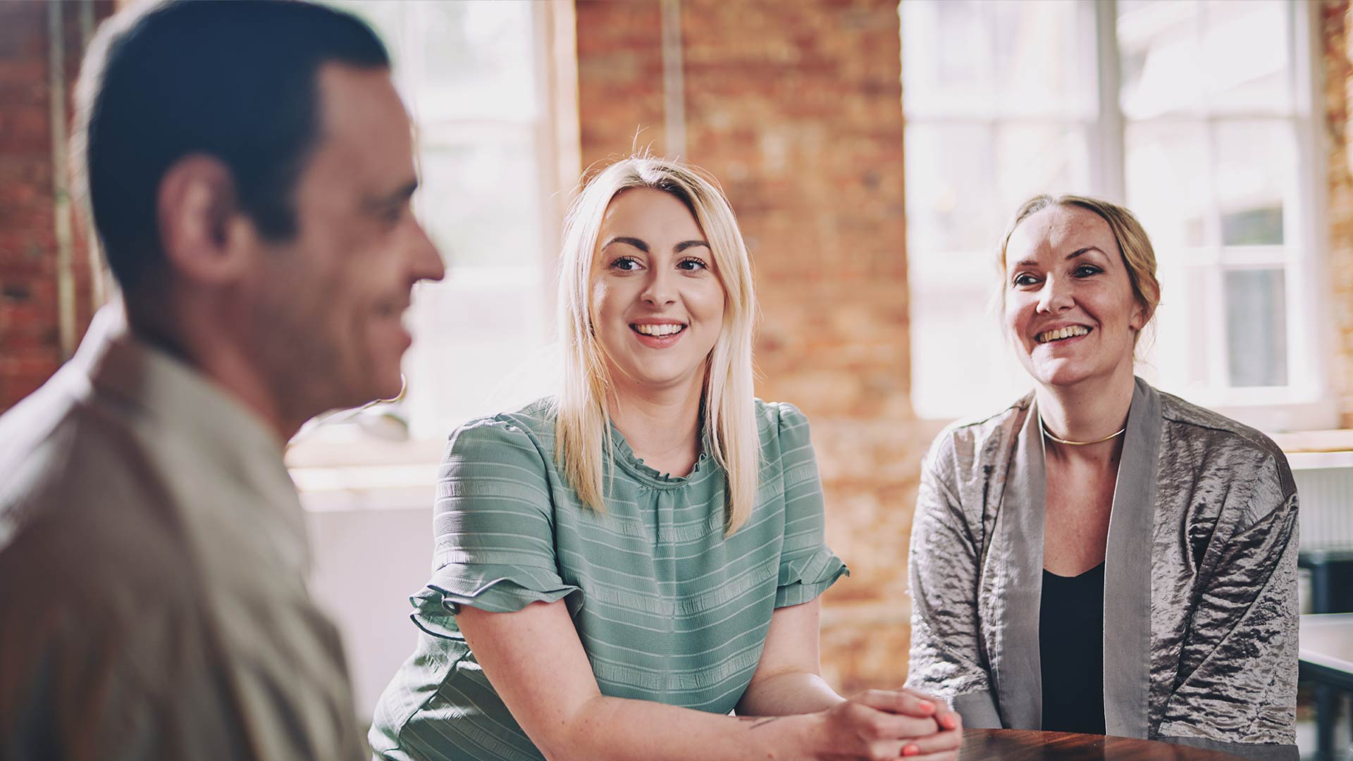 Three people are sitting together smiling