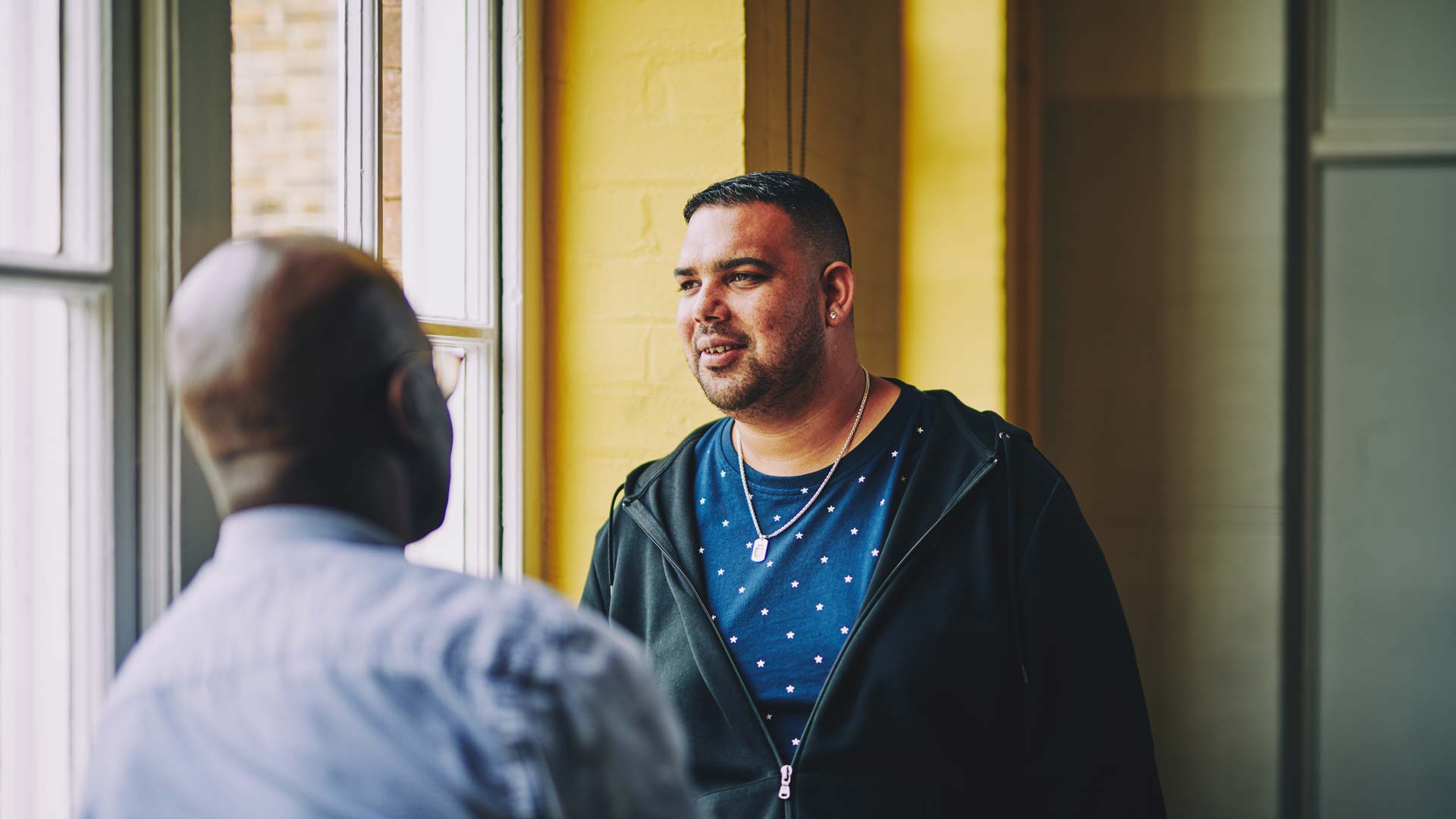 man having a conversation with another man and looking off into the distance