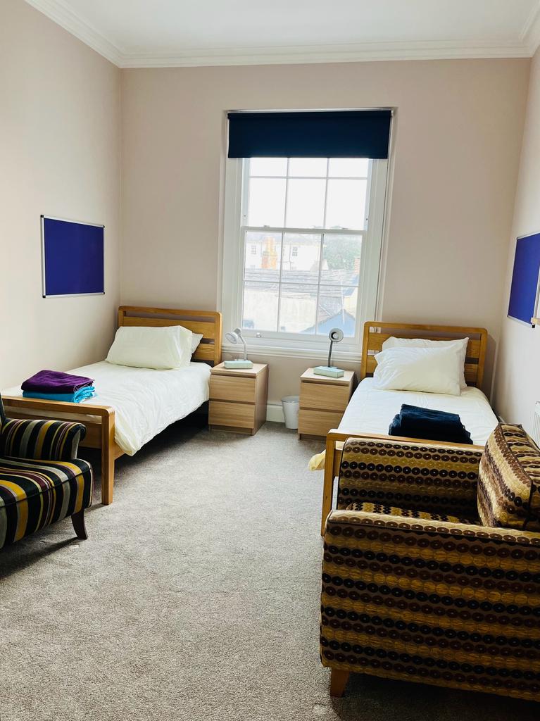 Bedroom - two single beds either side of window. The room has high ceilings and blue art on the walls and sofas at the end of each bed