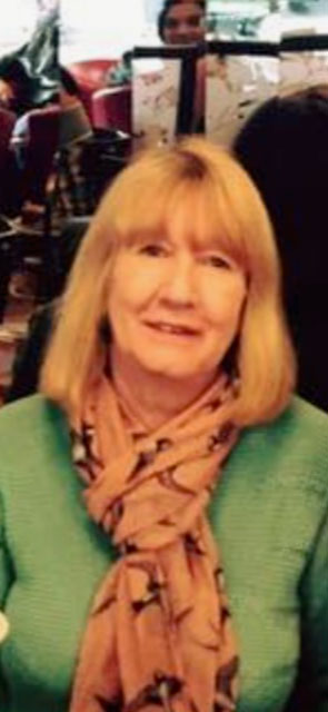 A photo of Liz - she is wearing a green top and a pink scarf