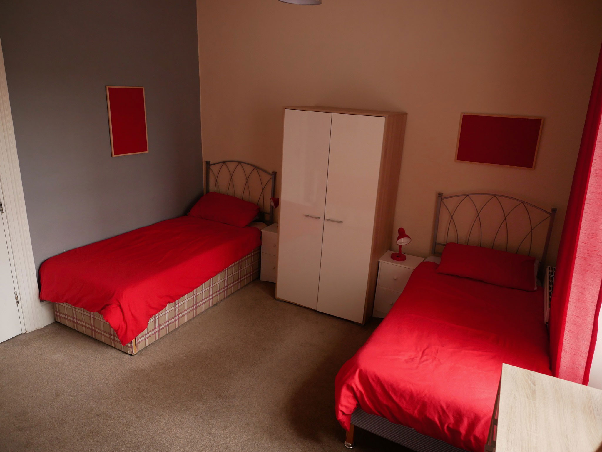 Western Counselling bedroom - a room with two single beds with red bedding and a white wardrobe