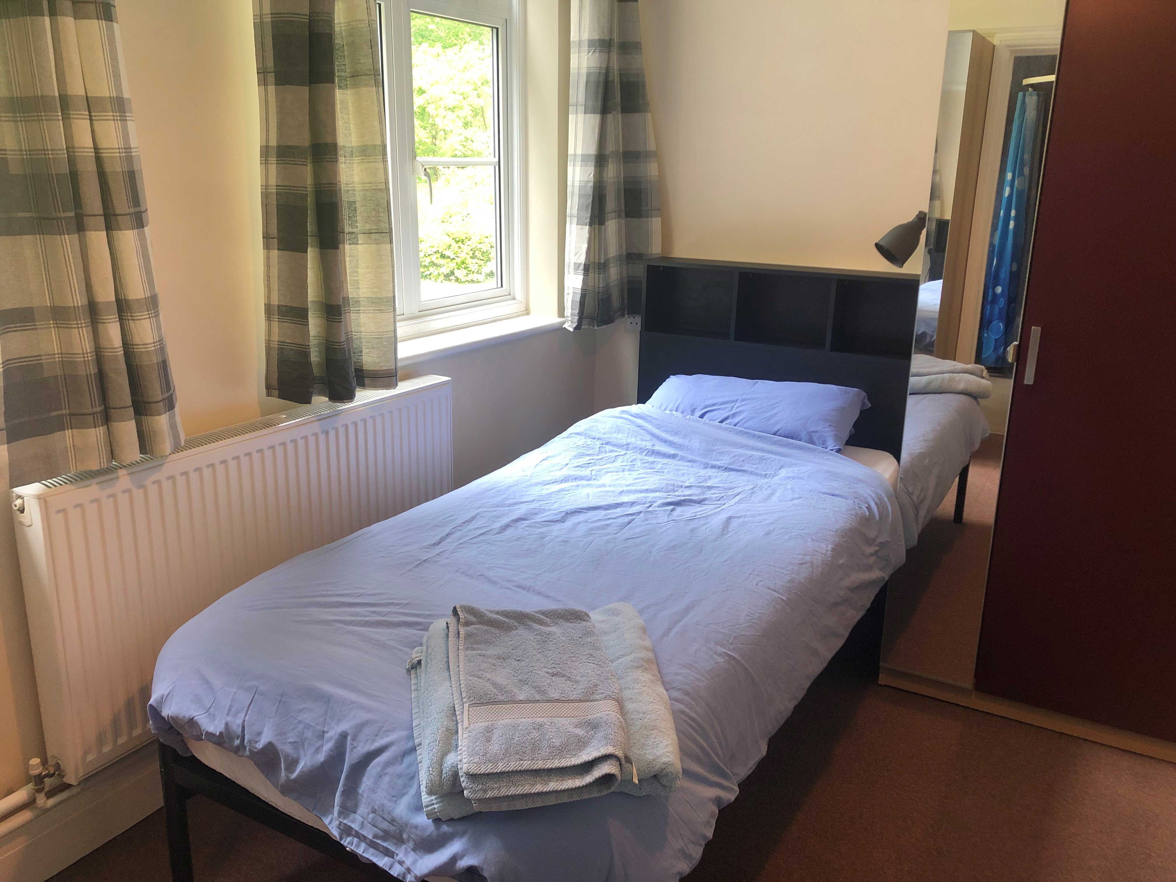 Bedroom - a single bed with a a window and green curtains