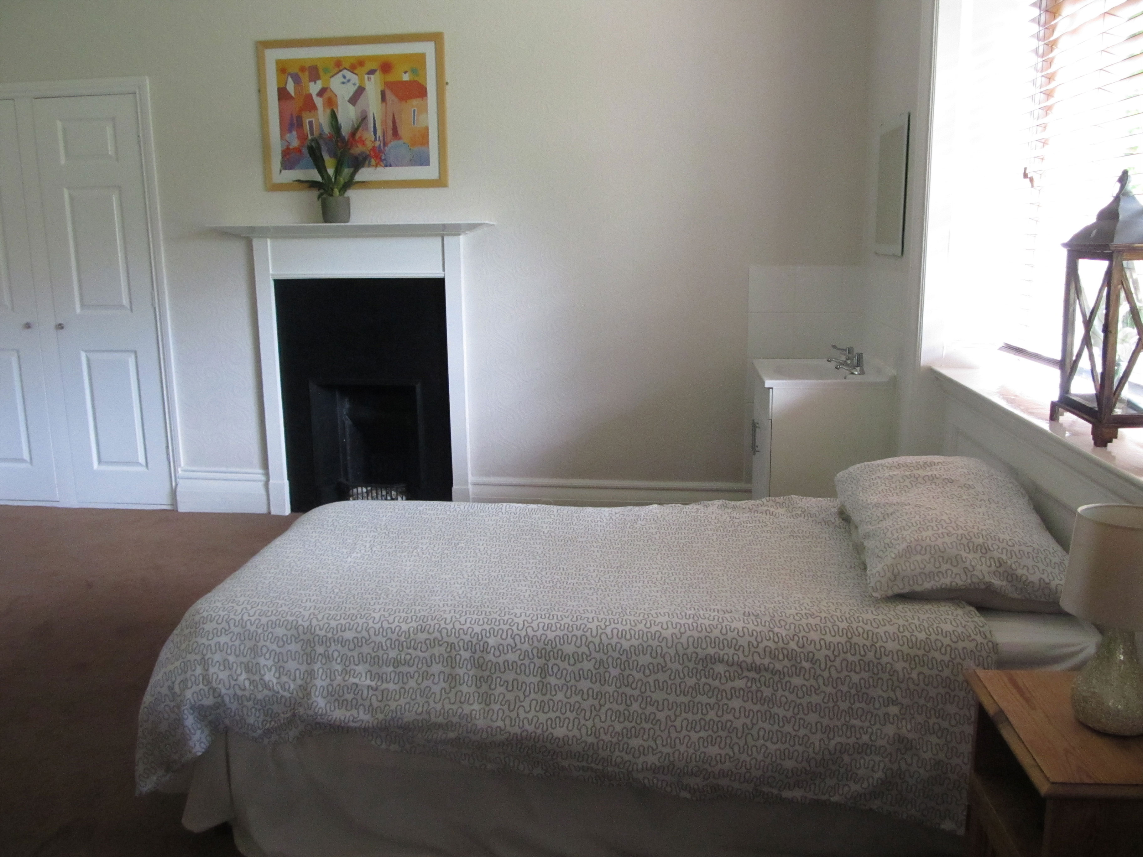 A bedroom  with white walls, a window and a single bed with white sheets