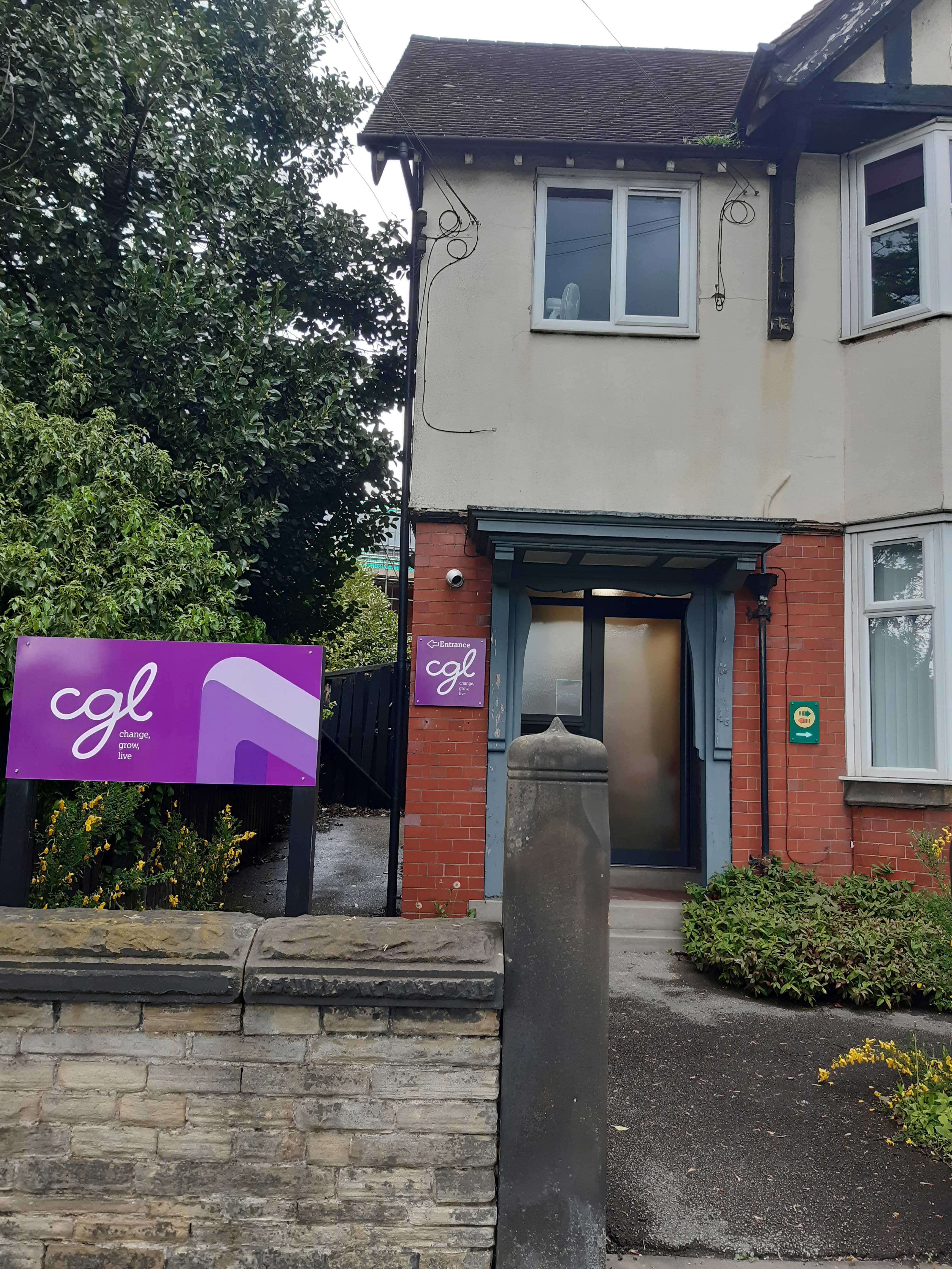Outside the Macclesfield Building - CGL sign, a wall, and a mock Tudor building