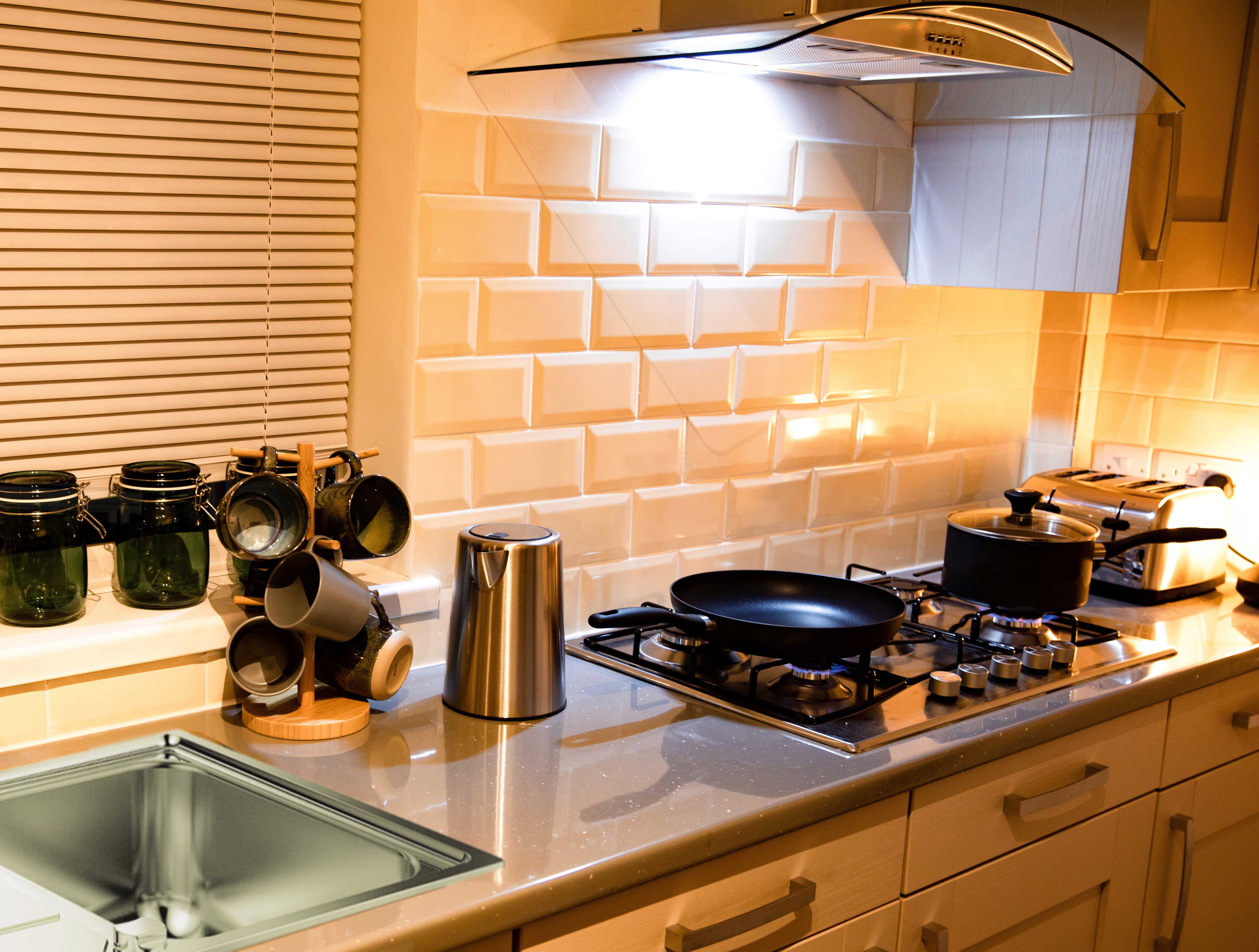 A kitchen with a gas stove top, sink, and toaster on the counters.