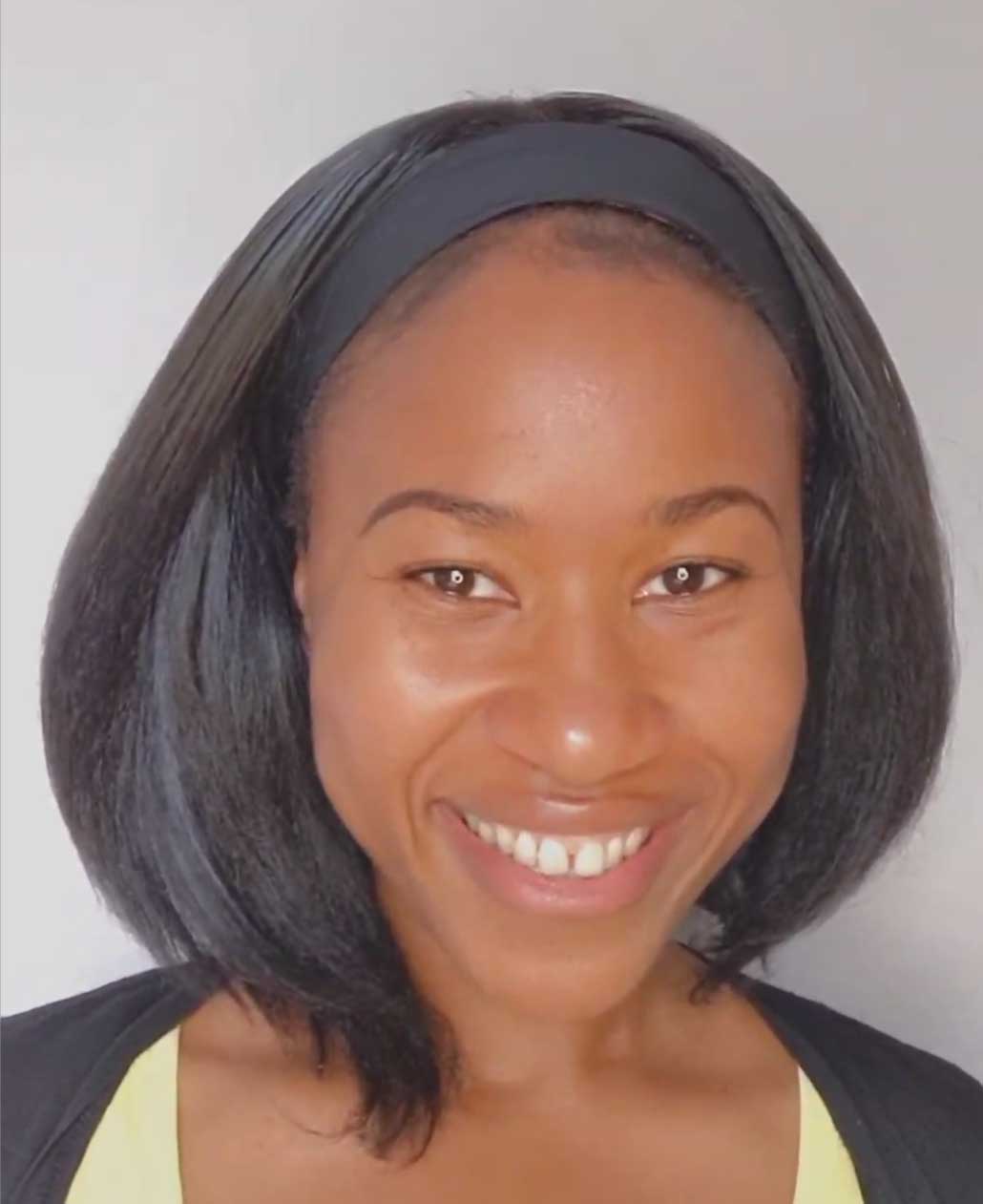 A black woman smiling at the camera, she has shoulder length dark hair