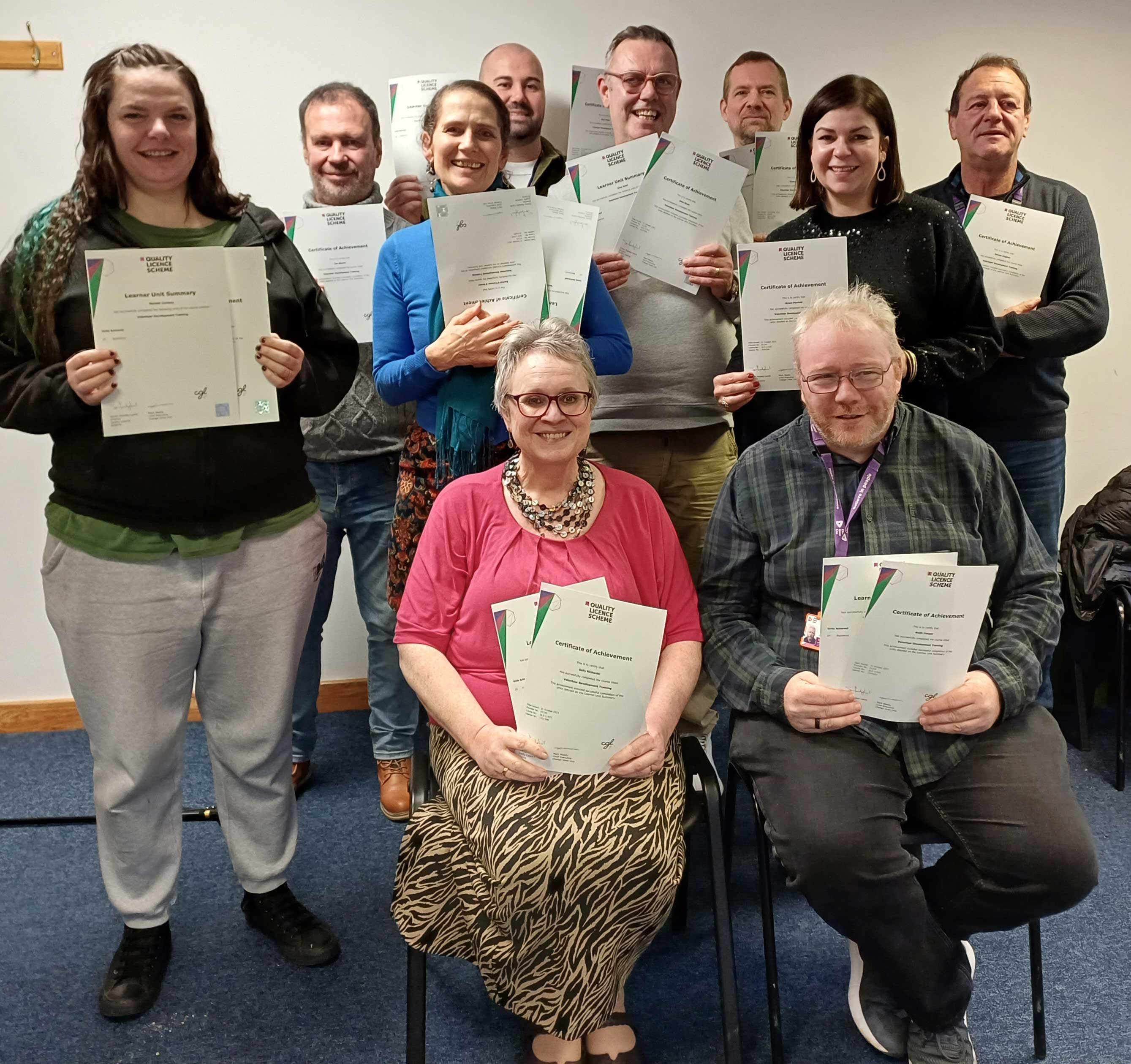 A group of people all holding up certificates to the camera