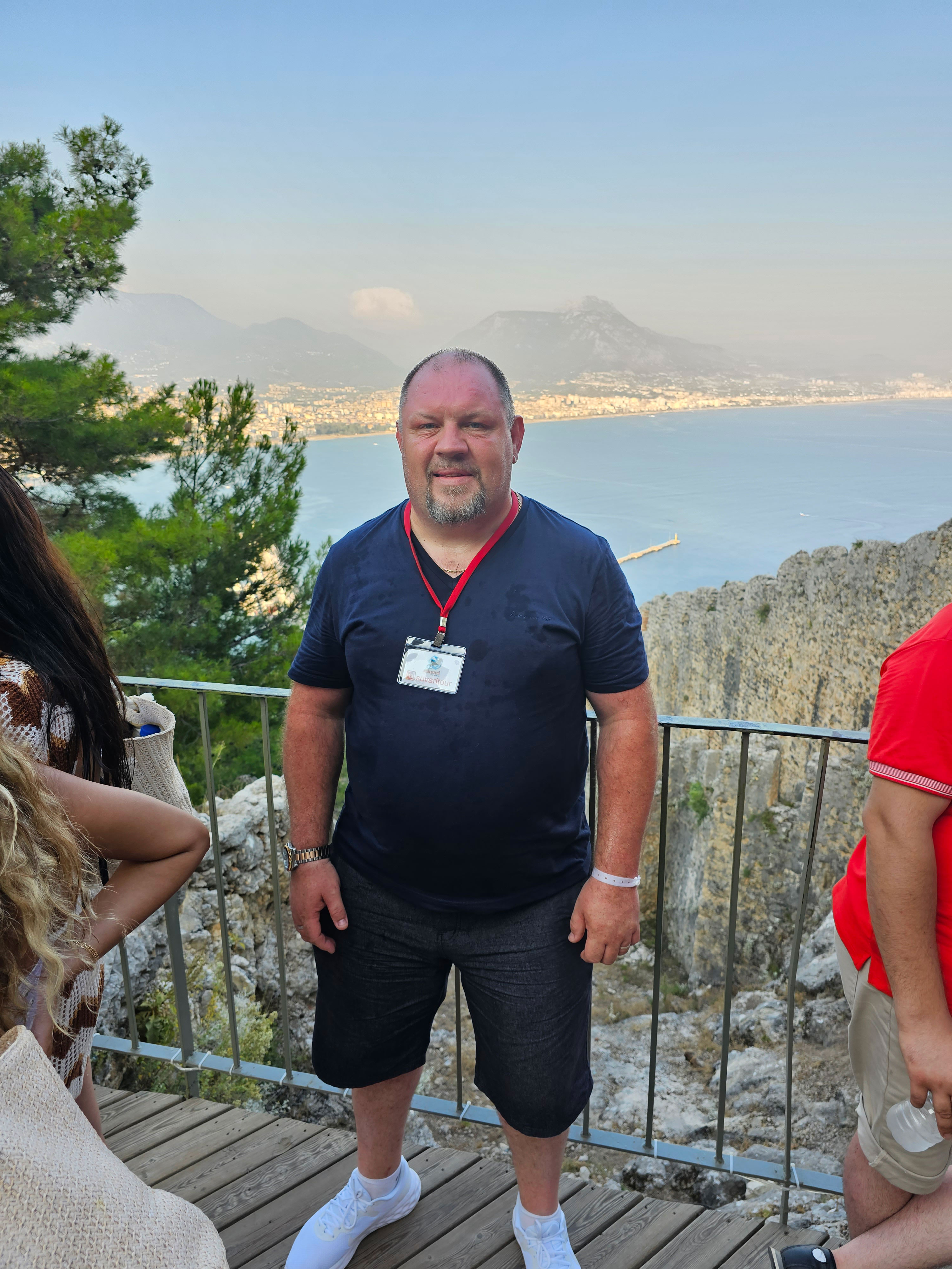 A man stood on the edge of a cliff with mountains in the background