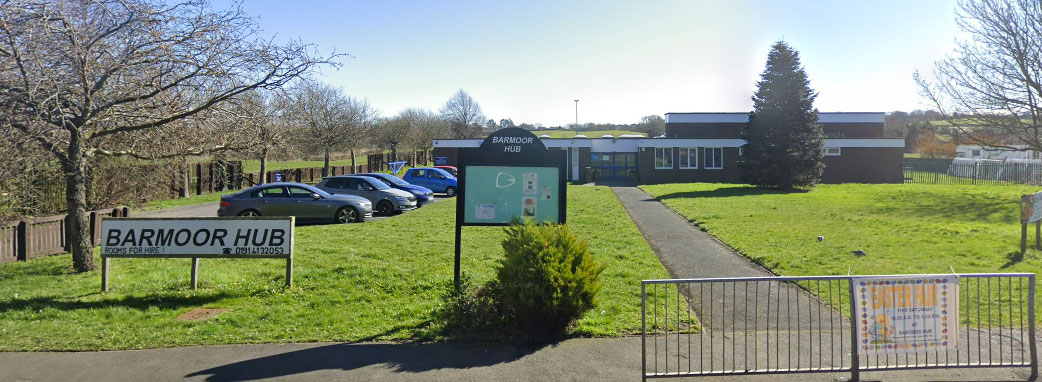 The outside of the building surrounded by grass and street signs