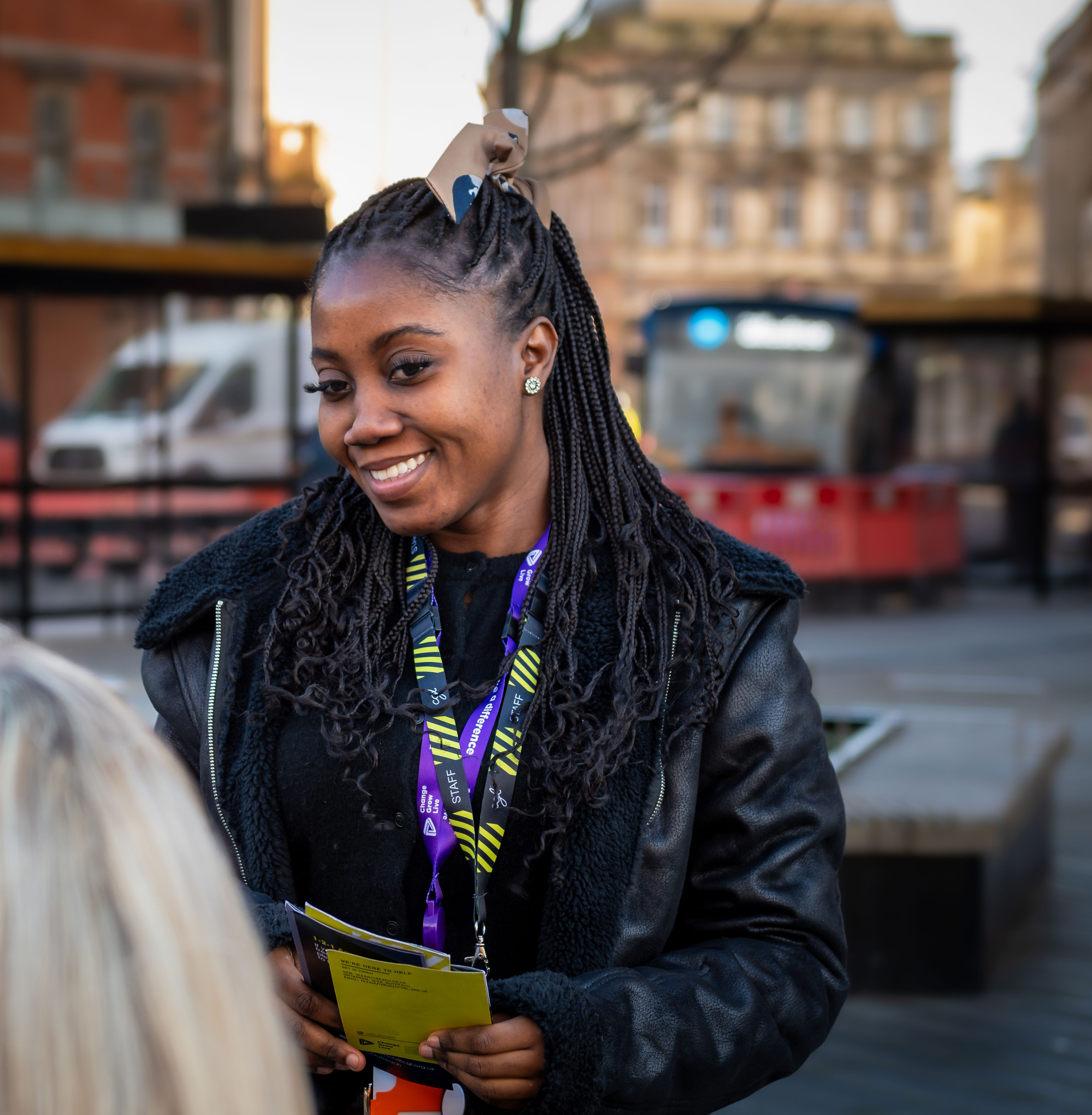 A young black woman outside smiling at someone off camera