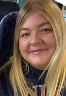  Annie has long blonde hair and is smiling at the camera