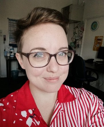  Tash has very short brown hair and is wearing a red shirt and glasses