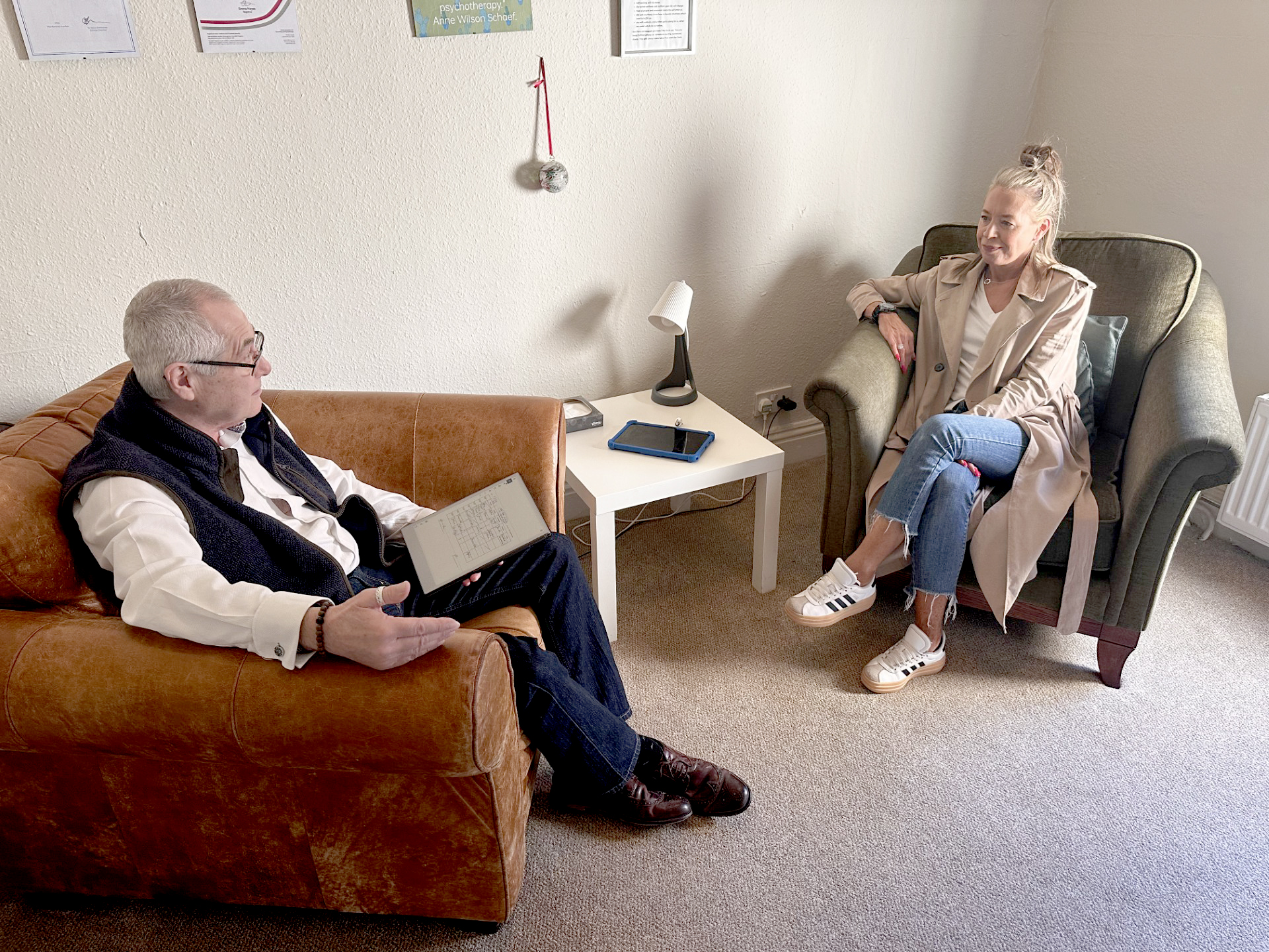 A man and a woman sat in arm chairs facing each other, engaged in a coversation