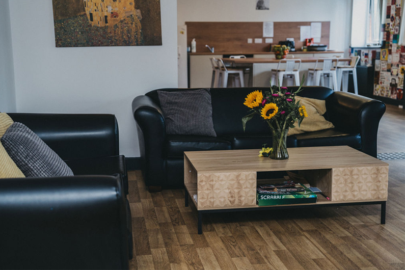 Two black leather sofas with a wooden coffee table in front