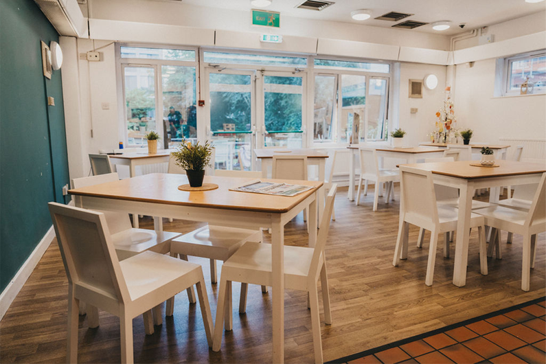 A large dining room with big windows and tables dotted around