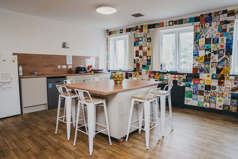 A kitchen area with an island and bar stools around for seating