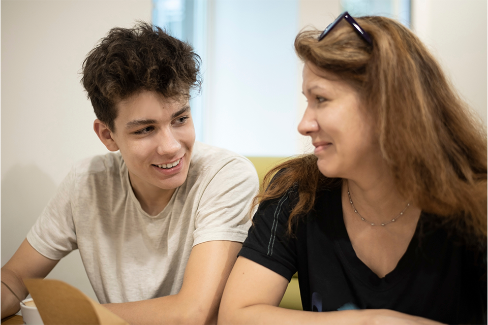 A young person talking to an adult and smiling