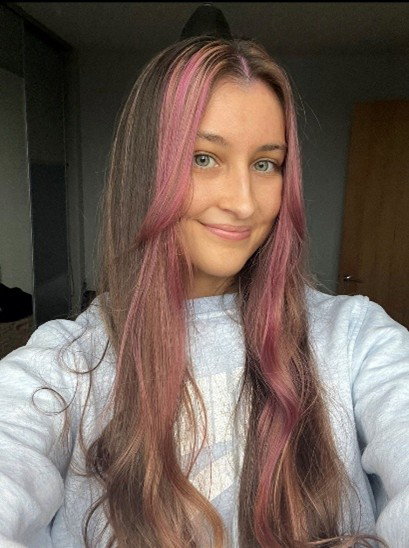 Gabby has long brown hair with a pink fringe