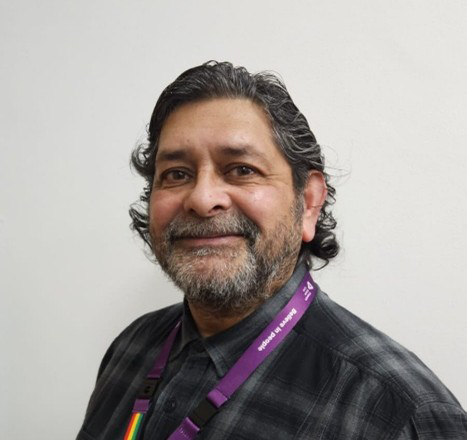 An older gentleman with greying hair and a beard is facing the camera side on