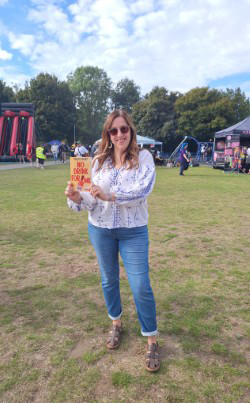 A woman stood in a field holding a book