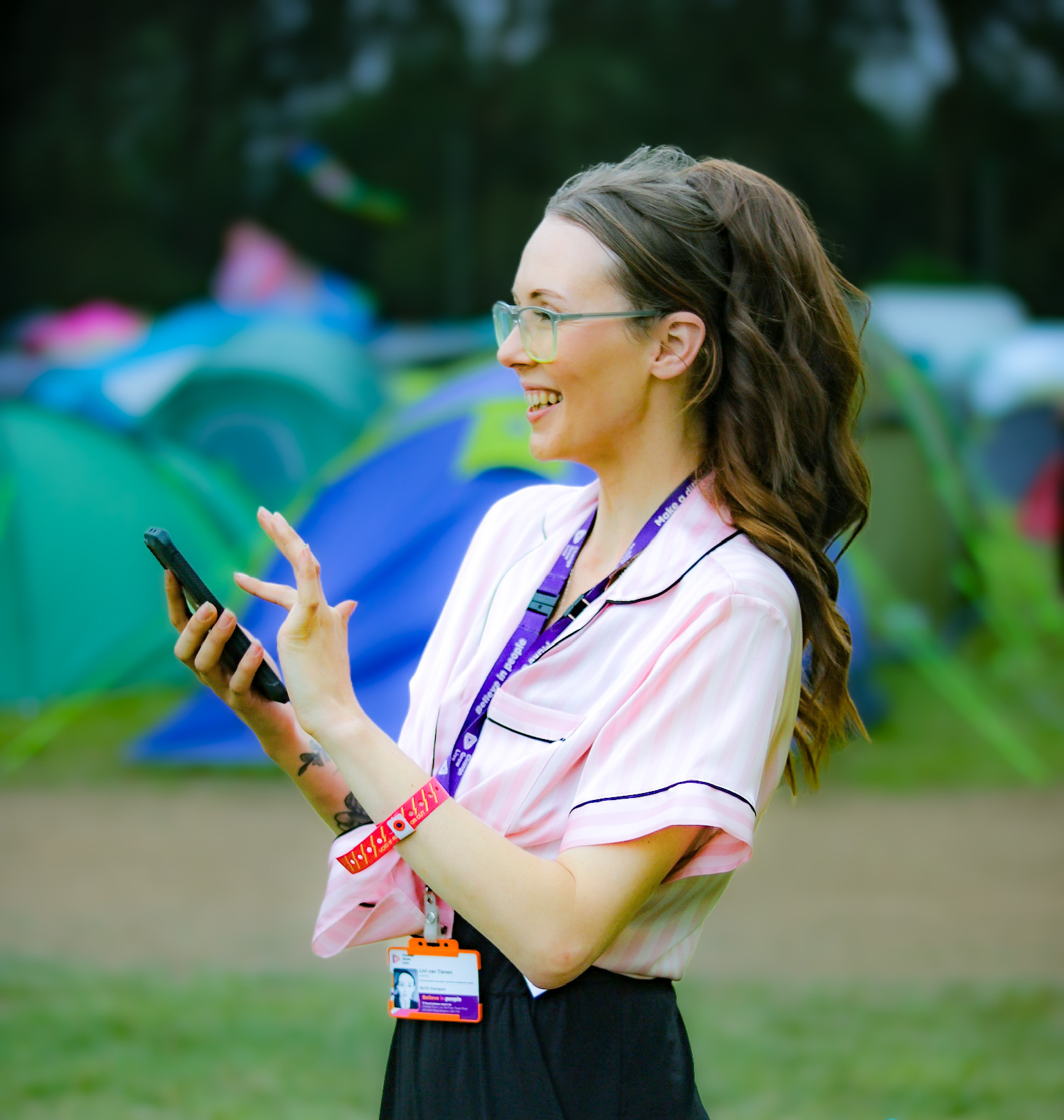 A young woman stood in front of some tents looking off to the side taking photos 