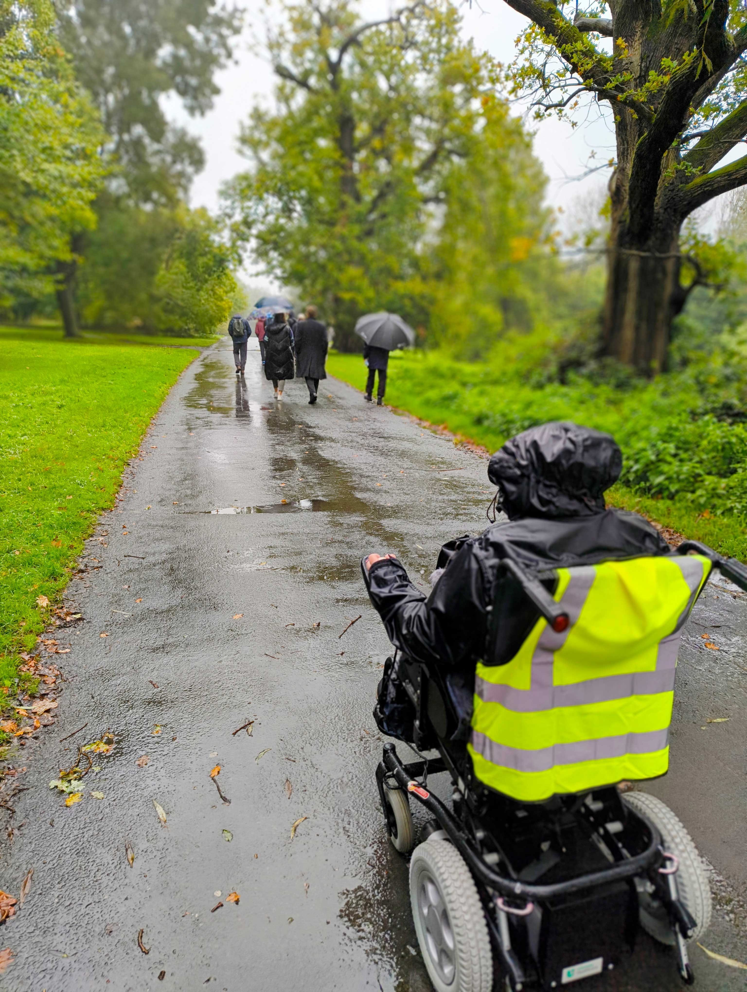 A rainy park with a person in an electric wheelchair