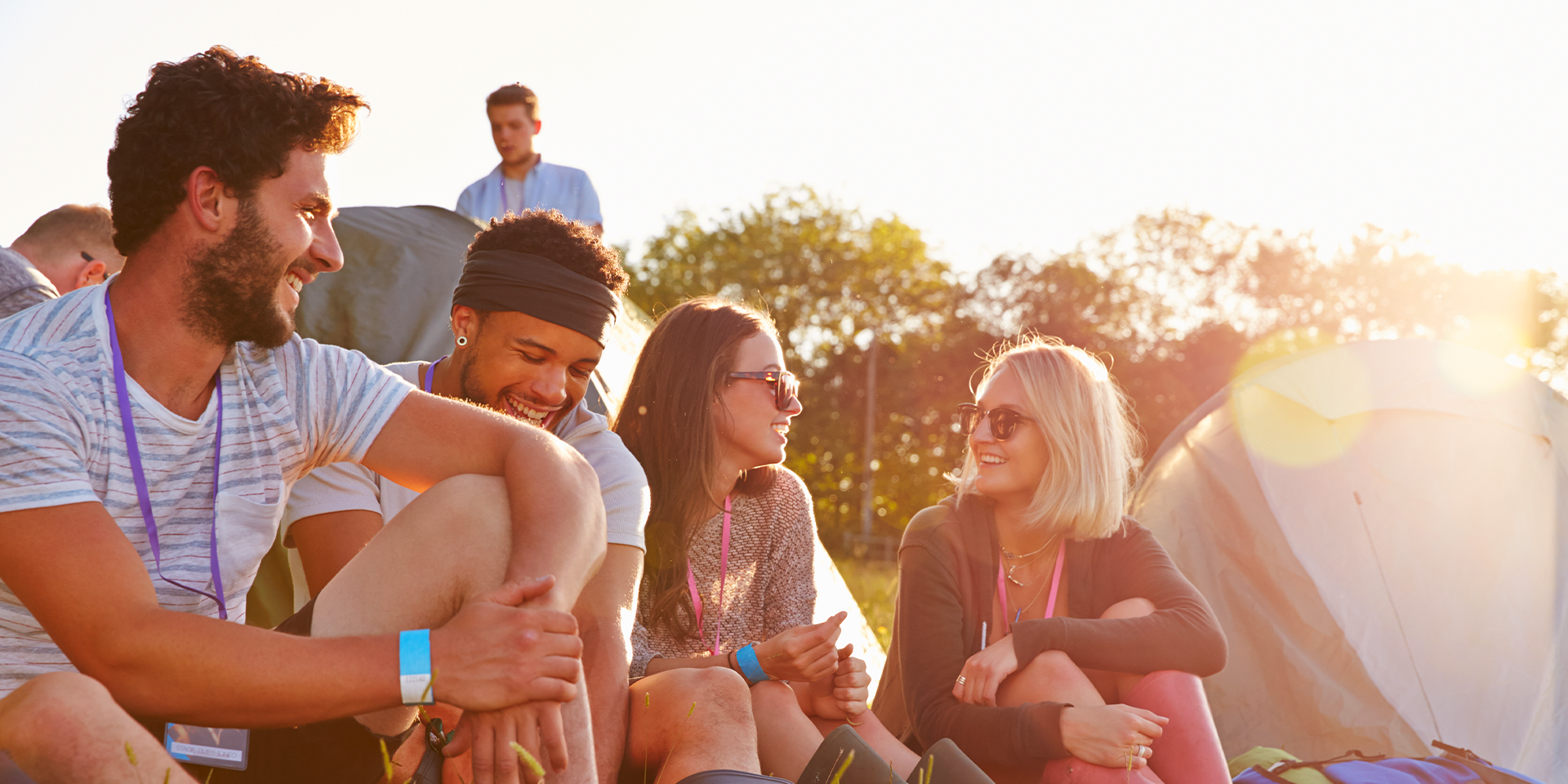 A group of young people sat in a field talking and laughing