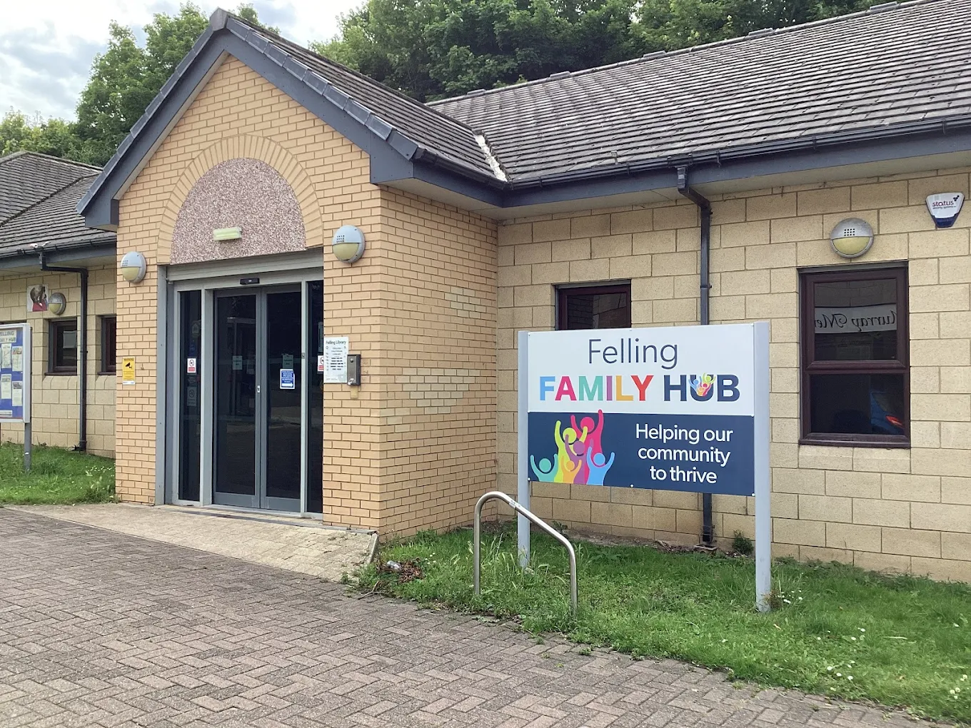 The outside of a yellow brick, single story building with a Felling Family Hub sign outside