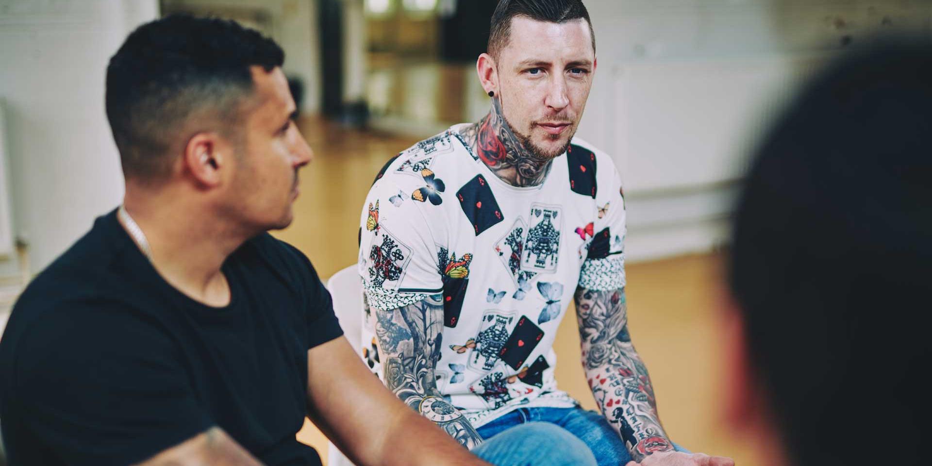 Two men sitting talking in a group