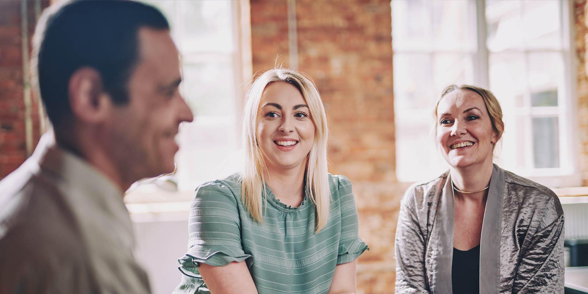 Three people are sitting together smiling