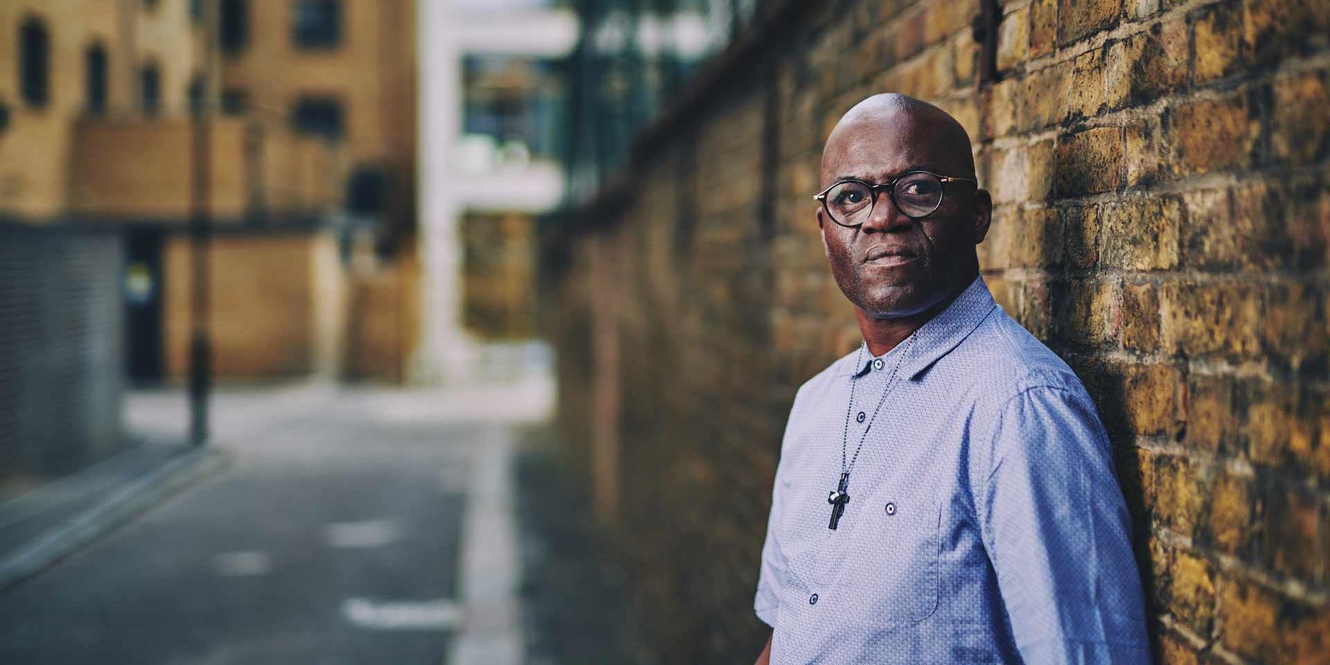 A man is standing next to a brick wall