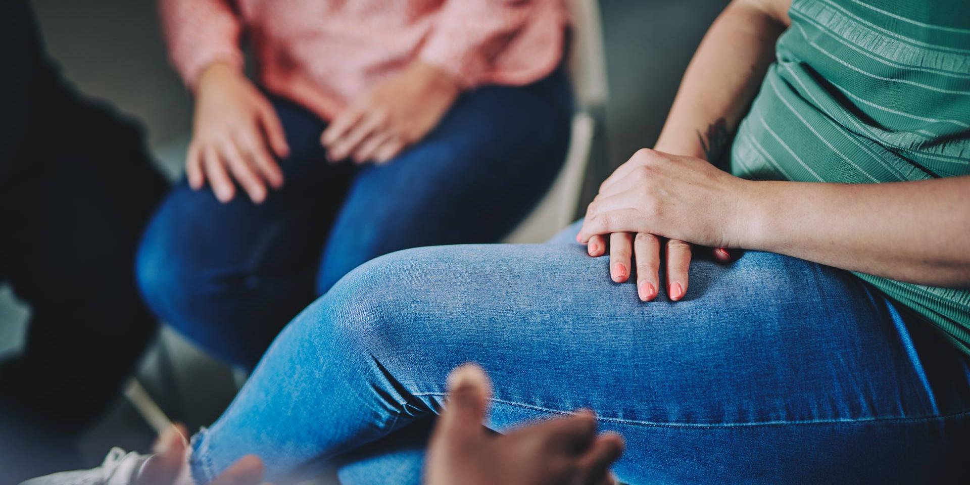 two women sitting - a photo of only their hands on their jeans