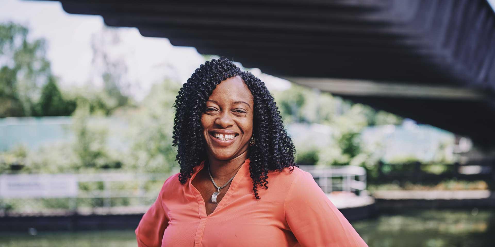 woman standing on a bridge smiling with water in the background