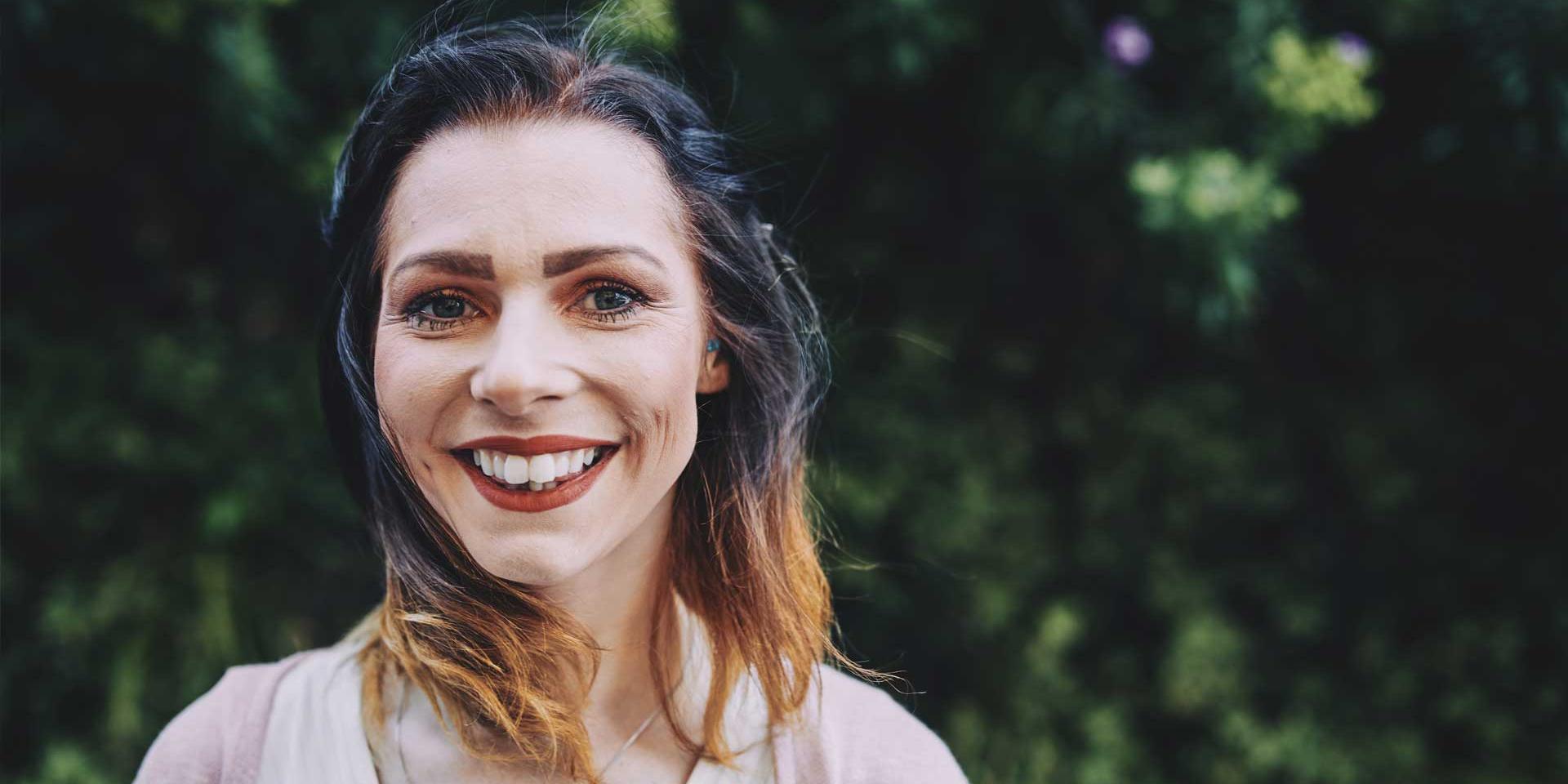 woman smiling standing in front of a tree