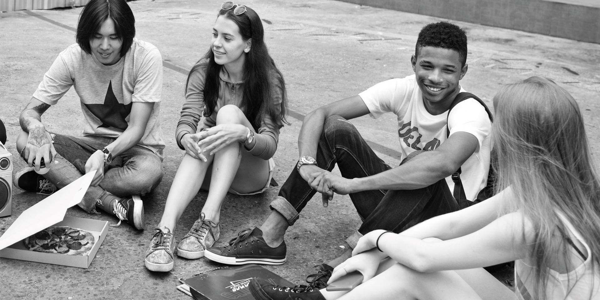 group of teenagers sitting around eating and talking