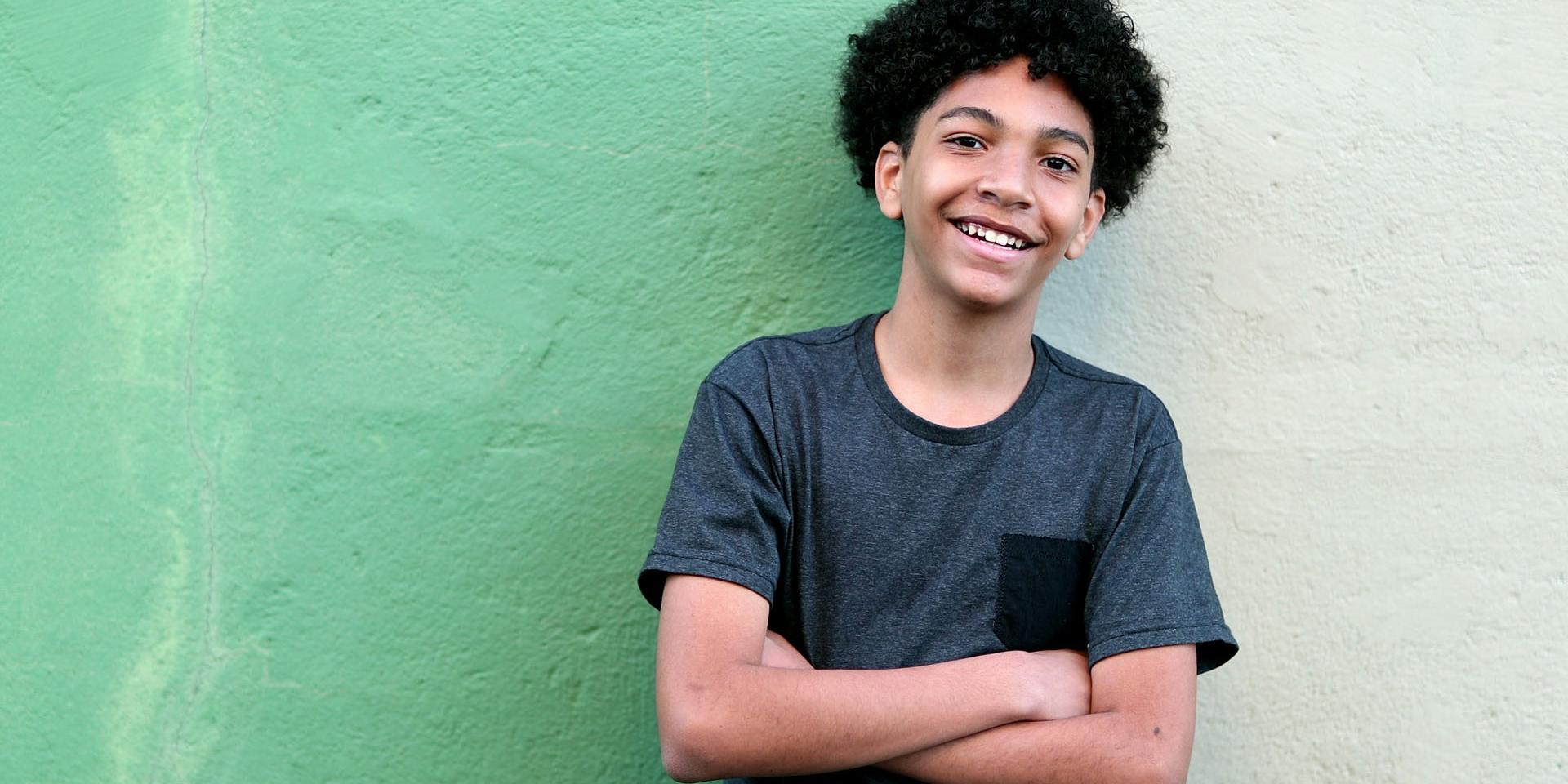 A young boy stood in front of a green wall