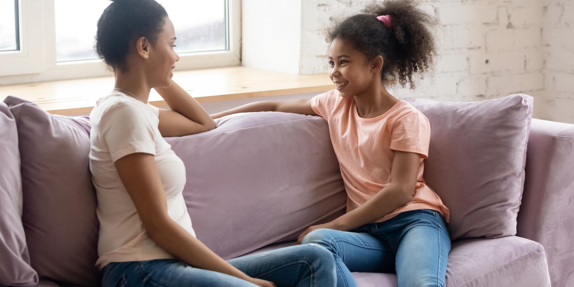 A woman and a child chatting while sat on a sofa