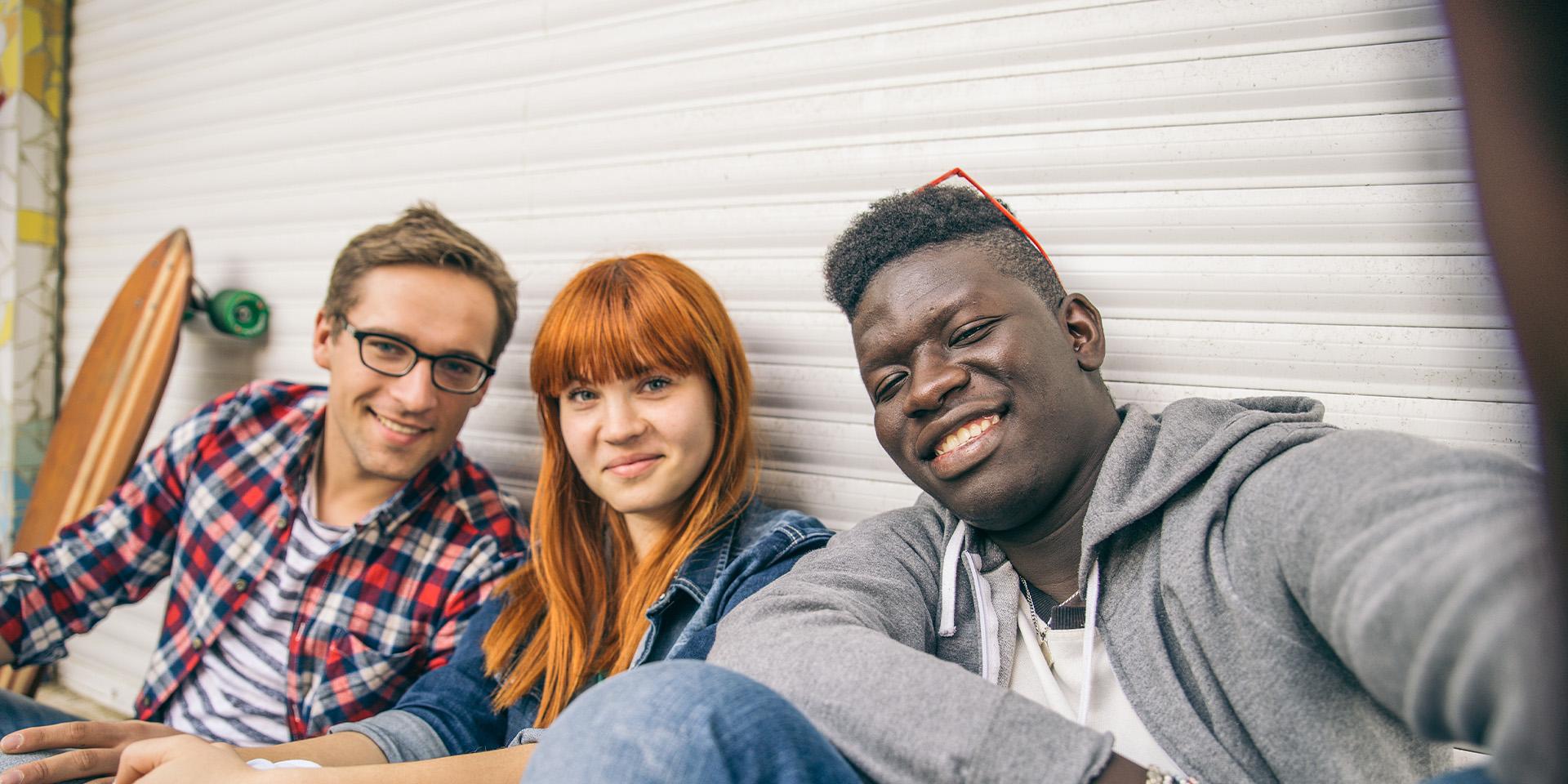 Three young people smiling and looking at camera
