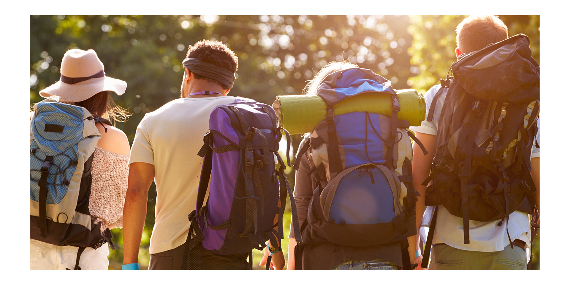 A group of people with backpacks on walking away from the camera