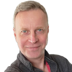 A man standing side on and looking at the camera over his shoulder. 