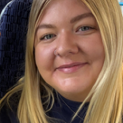 Annie has long blonde hair and is smiling at the camera