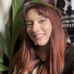 Bea has long reddish hair and is smiling at the camera