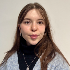 A young woman with long brown hair and a grey cardigan