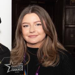 Chloe has long brown hair and is wearing a black top