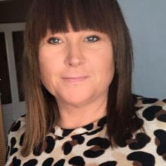 Kirsty has shoulder length brown hair with a full fringe