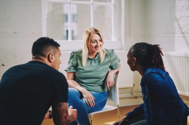 A woman and two men are sitting having a conversation