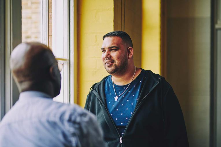 man having a conversation with another man and looking off into the distance