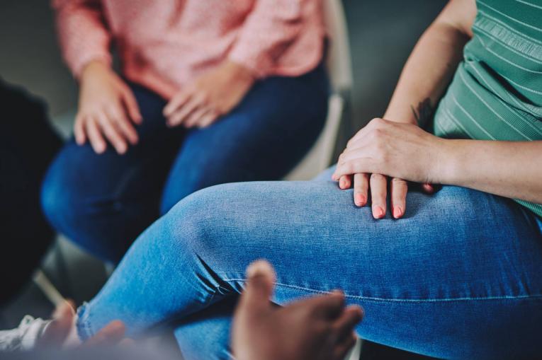 two women sitting - a photo of only their hands on their jeans