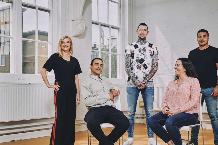 group of five people sitting and standing smiling