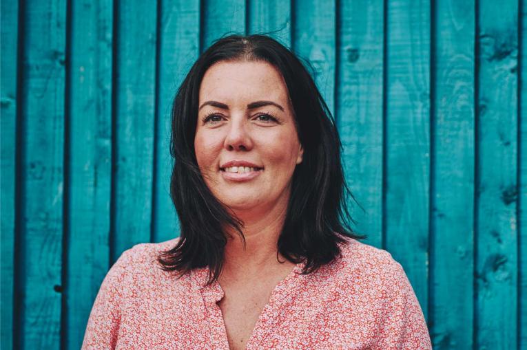 woman smiling standing against a blue wooden wall
